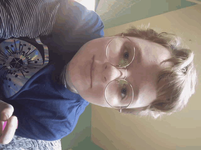 a person wearing glasses and a blue shirt with a cd on the shoulder