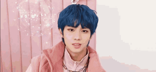 a boy with blue hair is wearing a pink jacket and a necklace .