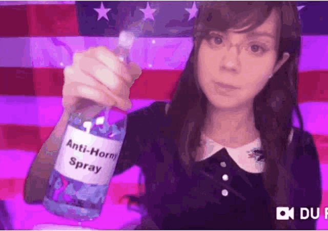 a woman is holding a bottle of anti-horn spray in her hand in front of an american flag .