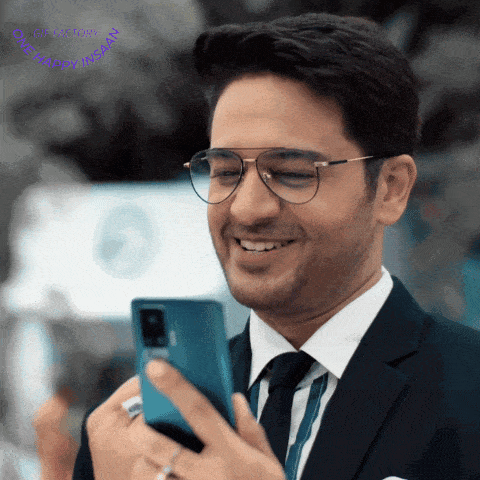 a man in a suit and tie is smiling and looking at his phone