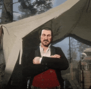 a man in a suit is standing in front of a tent with his arms crossed
