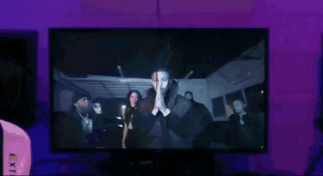 a group of people standing in front of a tv screen that says ' x ' on it