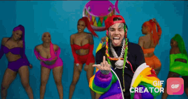 a man in a rainbow jacket stands in front of a group of women dancing ..