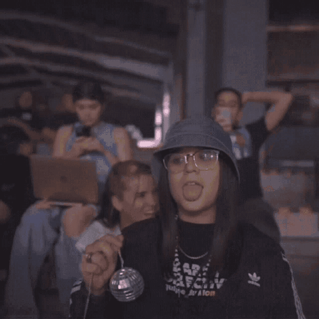a woman wearing a denim hat and glasses giving the middle finger