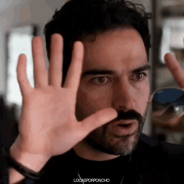 a man with a beard is making a funny face with his hands .