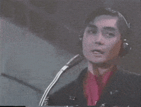 a man wearing headphones and a red shirt is singing into a microphone .