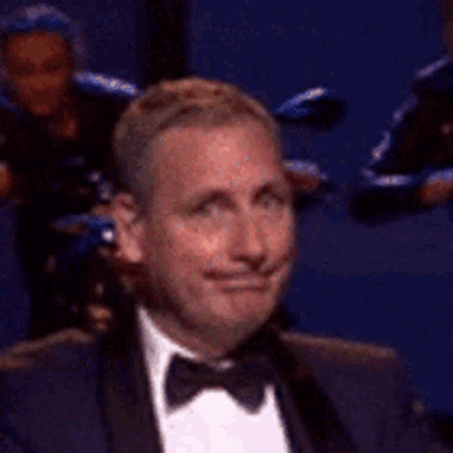 a man in a tuxedo and bow tie is making a face