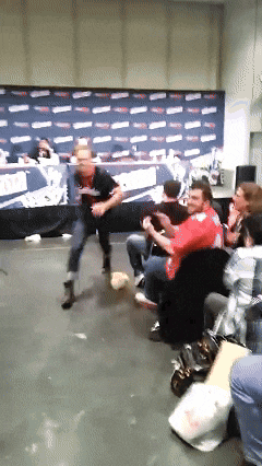 a man in a red shirt is dancing in front of a sign that says ' xfinity ' on it