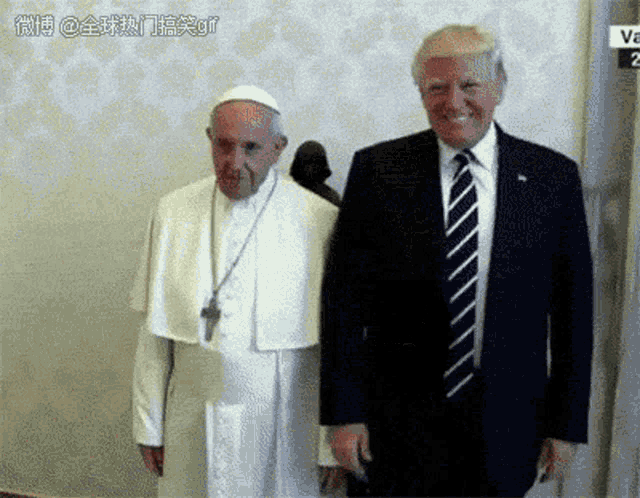 a man in a suit and tie standing next to a man in a white robe