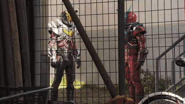 a man in a red suit is standing next to a man in a black suit behind a fence