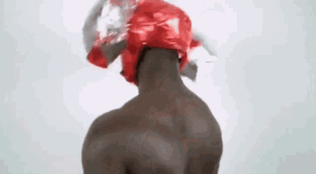 a man without a shirt is wearing a red helmet with a candy on it .