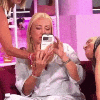 a woman is sitting on a couch taking a picture of herself with a cell phone .