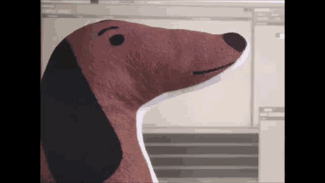 a stuffed dachshund is sitting in front of a computer