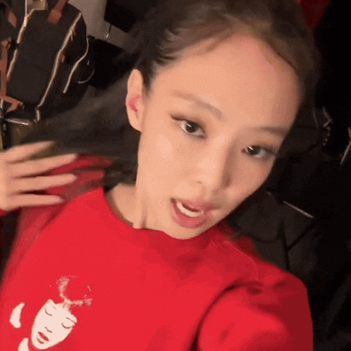 a woman wearing a red sweatshirt with a face on it is taking a selfie .