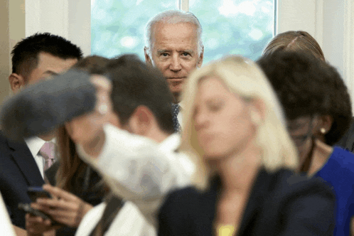 a man in a suit and tie stands in a crowd