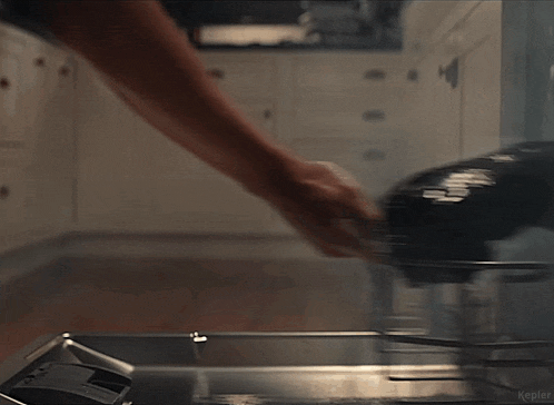a man in a white tank top is standing in a kitchen holding a bottle