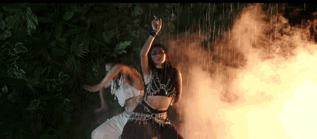 a woman is dancing in the rain with a fire in the background .