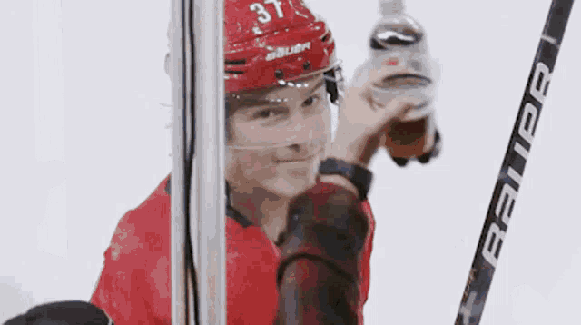 a hockey player with the number 37 on his helmet is holding a bauer stick