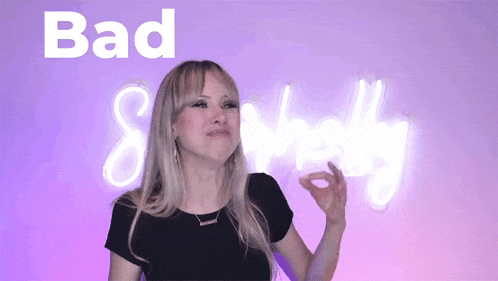 a woman is standing in front of a neon sign that says bad