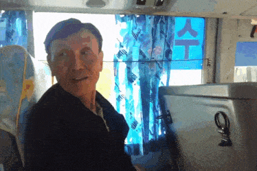 a man sits in front of a window with a blue sign that says ' t ' on it