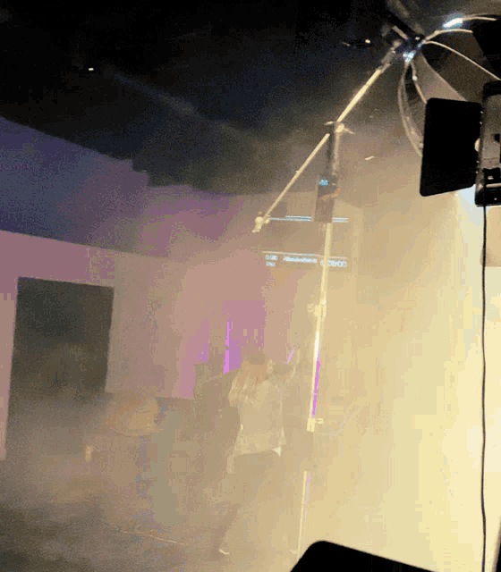 a person is standing in a room with smoke coming out of the ceiling and a microphone in the foreground