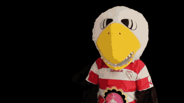 a mascot wearing a red and white striped shirt with a flower on the chest