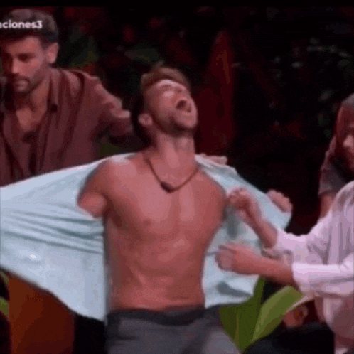 a man without a shirt is being held by a group of men .