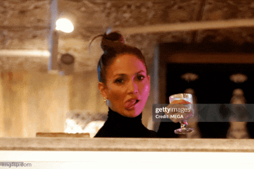 a woman sticking her tongue out and holding a glass of wine