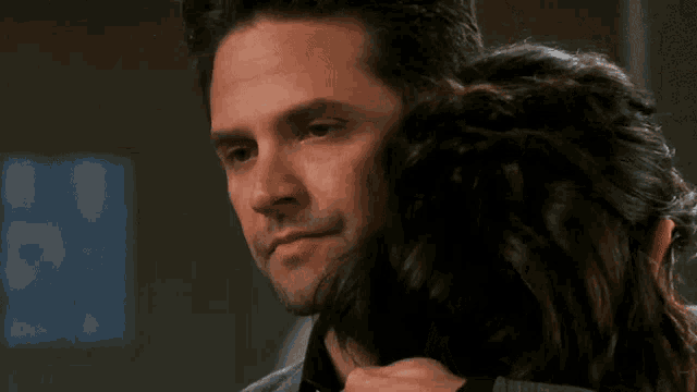 a man with his eyes closed is hugging a woman