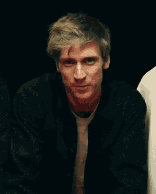 a man with blonde hair is wearing a black shirt and white shirt