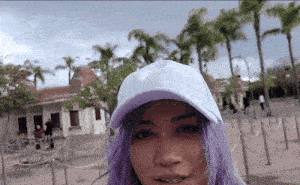 a woman with purple hair wears a white hat