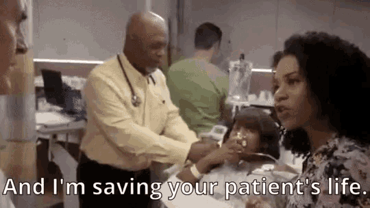 a doctor is talking to a little girl in a hospital bed while a nurse watches .