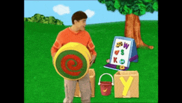 a man in an orange shirt is standing next to a bucket and a box that says y on it