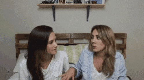 two women are sitting next to each other on a bed .