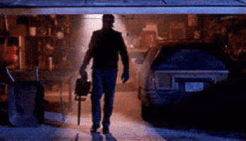 a man is walking out of a garage with a briefcase and a knife .