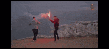 a man in a red jacket holds a red flare in his hand