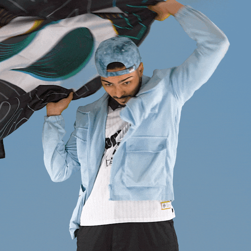 a man wearing a hat and a light blue jacket holds a scarf