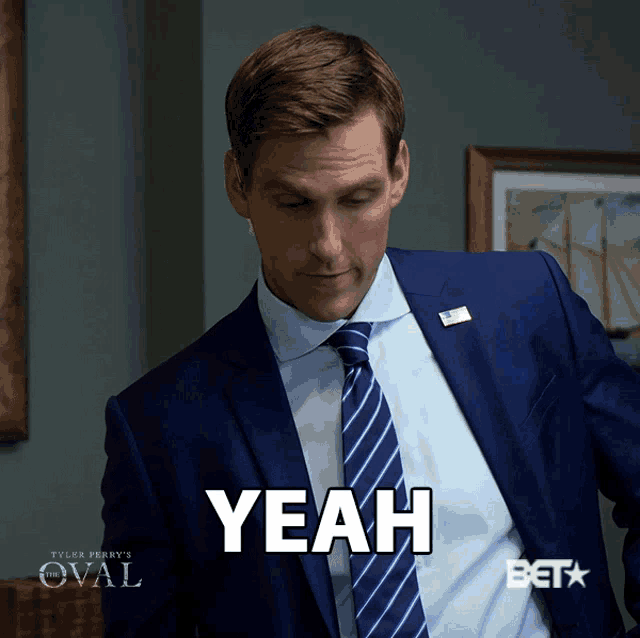 a man in a suit and tie with the word yeah on his chest