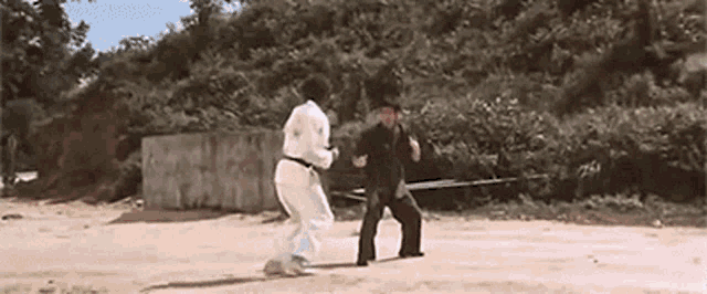 a man in a white karate uniform is fighting another man in a black karate uniform