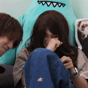 a man and a woman are sitting next to each other and the woman is covering her mouth