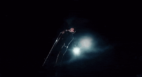 a man in a black jacket is singing into a microphone .