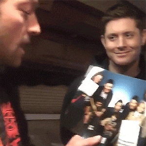 a man is holding a picture of a group of people and smiling at the camera