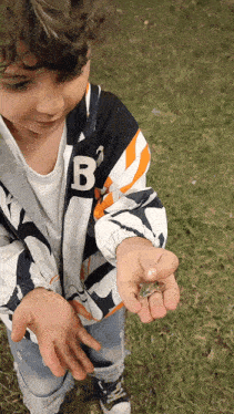 a young boy wearing a jacket with the letter b on the front