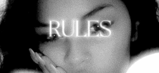 a black and white photo of a woman covering her face with her hand and the word rules written in white letters .
