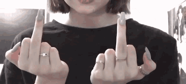 a woman with rings on her fingers is making a middle finger sign .