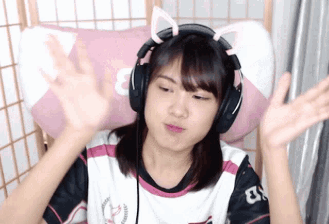a young girl wearing headphones with cat ears on her head is sitting in a chair .