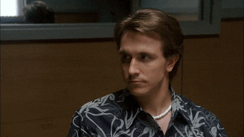 a man wearing a pearl necklace and a patterned shirt
