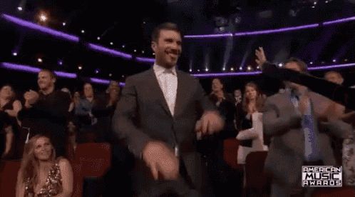a man in a suit is dancing in front of an audience at the american music awards .