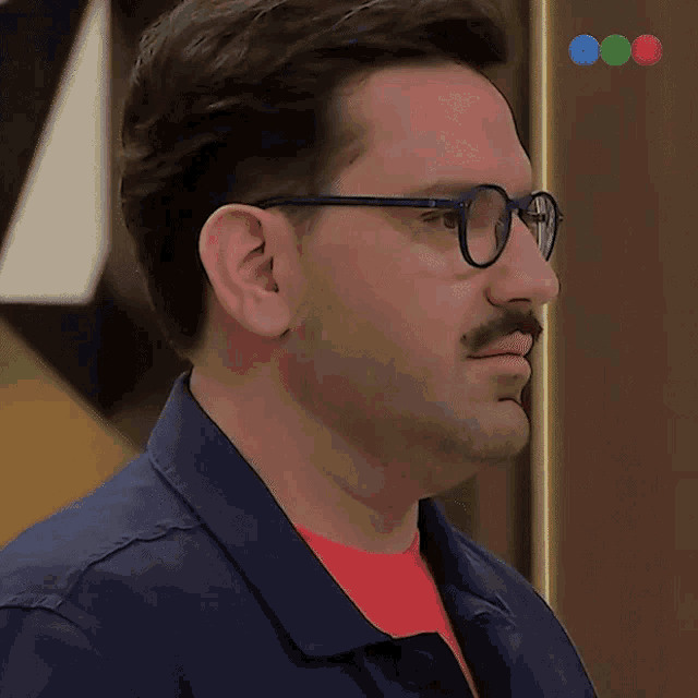 a man wearing glasses and a mustache looks to his left
