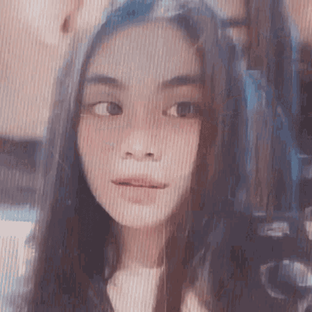 a close up of a girl 's face with long hair and a striped background .